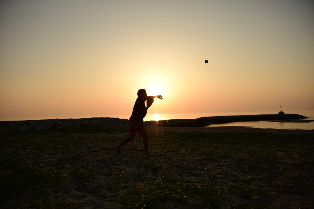 一眼レフで撮影した夕方の海辺でボールを投げる人